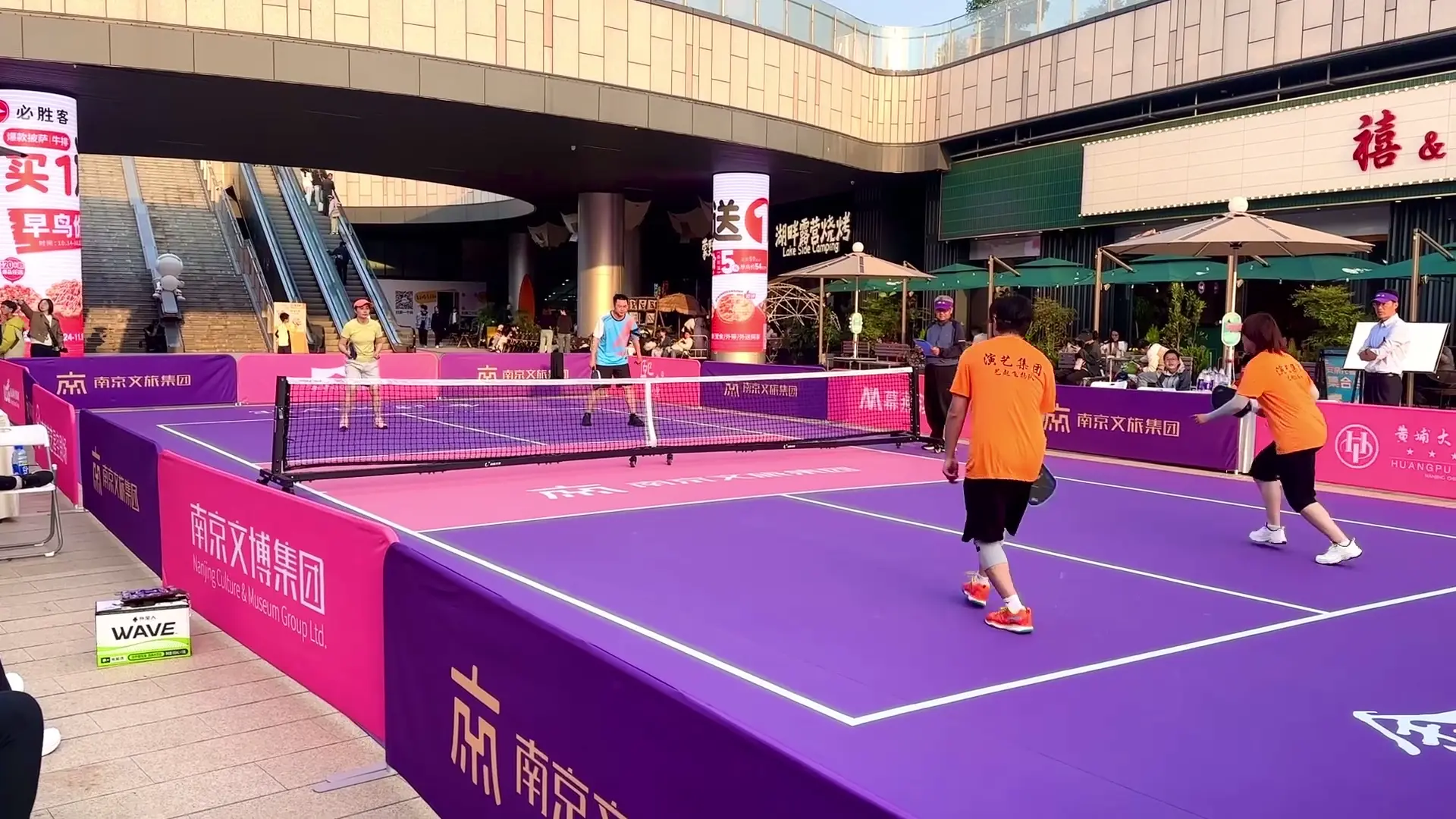 A pickleball doubles match at an outdoor shopping mall